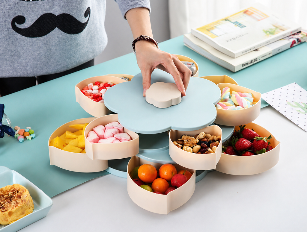 Drehbare Snackbox Blütenform in Blau – Hand dreht den Deckel, 10 Fächer mit Früchten und Snacks gefüllt